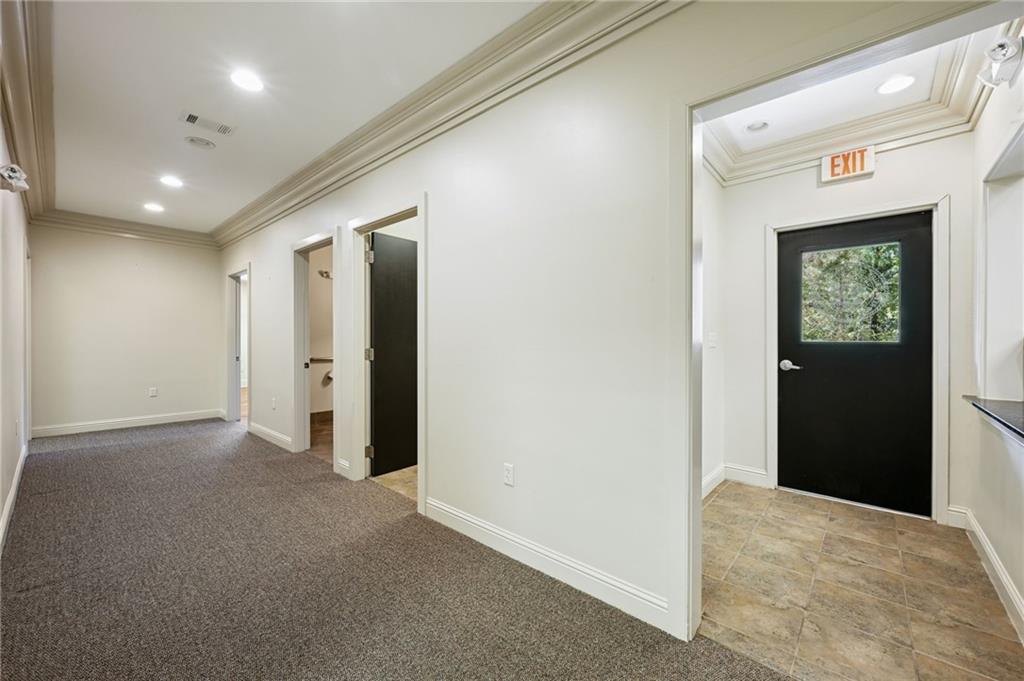 Empty hallway with gray carpeting, ornate ceiling trim, and a black EXIT door.