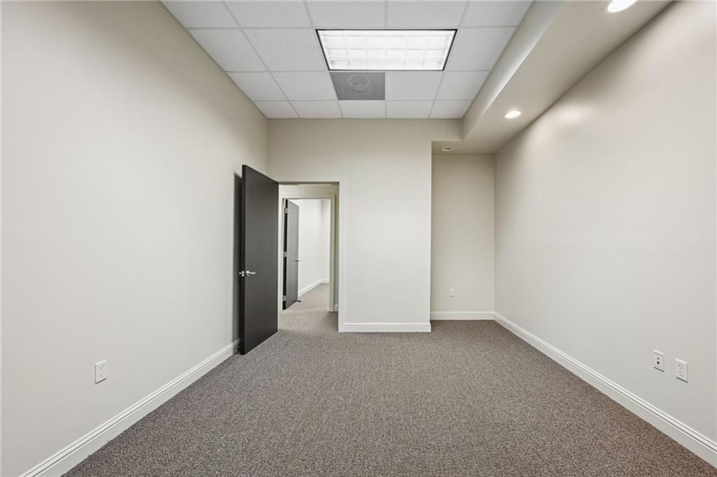 Vacant carpeted room with recessed lights and an open door to a second room.