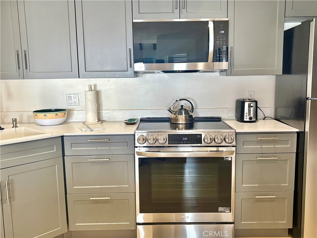Kitchen with gray cabinets, light countertops, and stainless steel appliances.