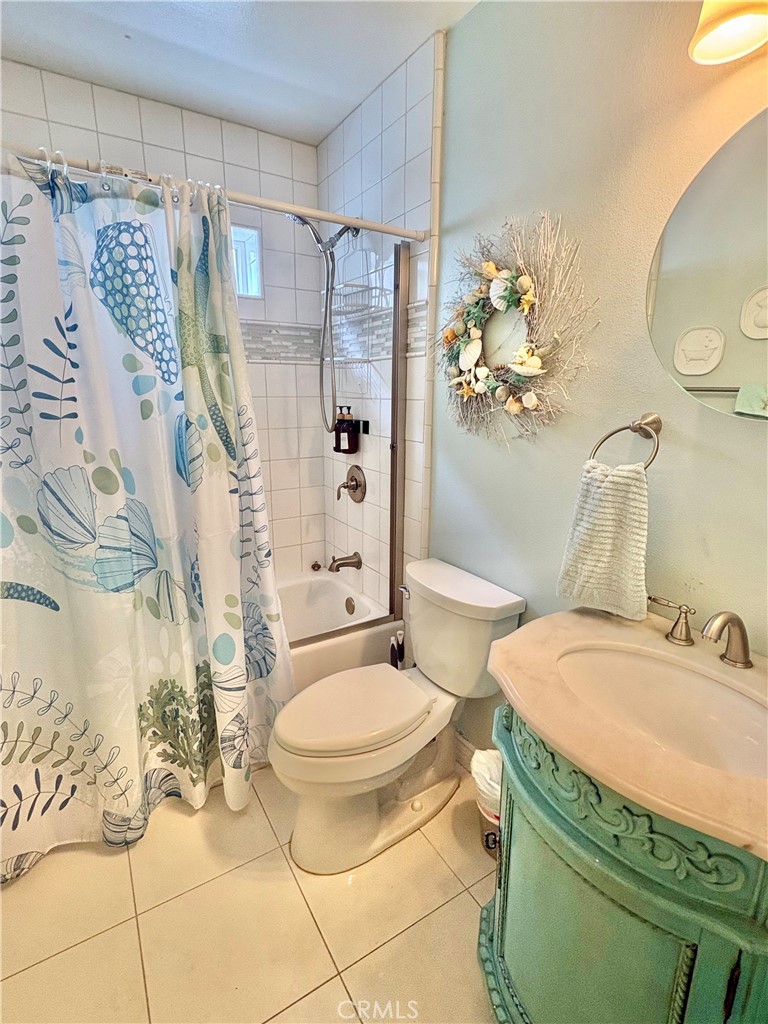 Bathroom with a tiled tub and shower, sea-life curtain, and ornate turquoise vanity.