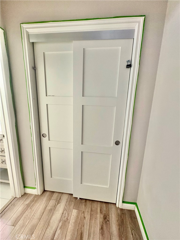White paneled sliding closet doors with recessed pulls and wood-look flooring.