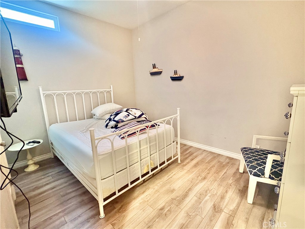 Bedroom with a white metal bed, nautical bedding, ship decorations, and light wood-look flooring.