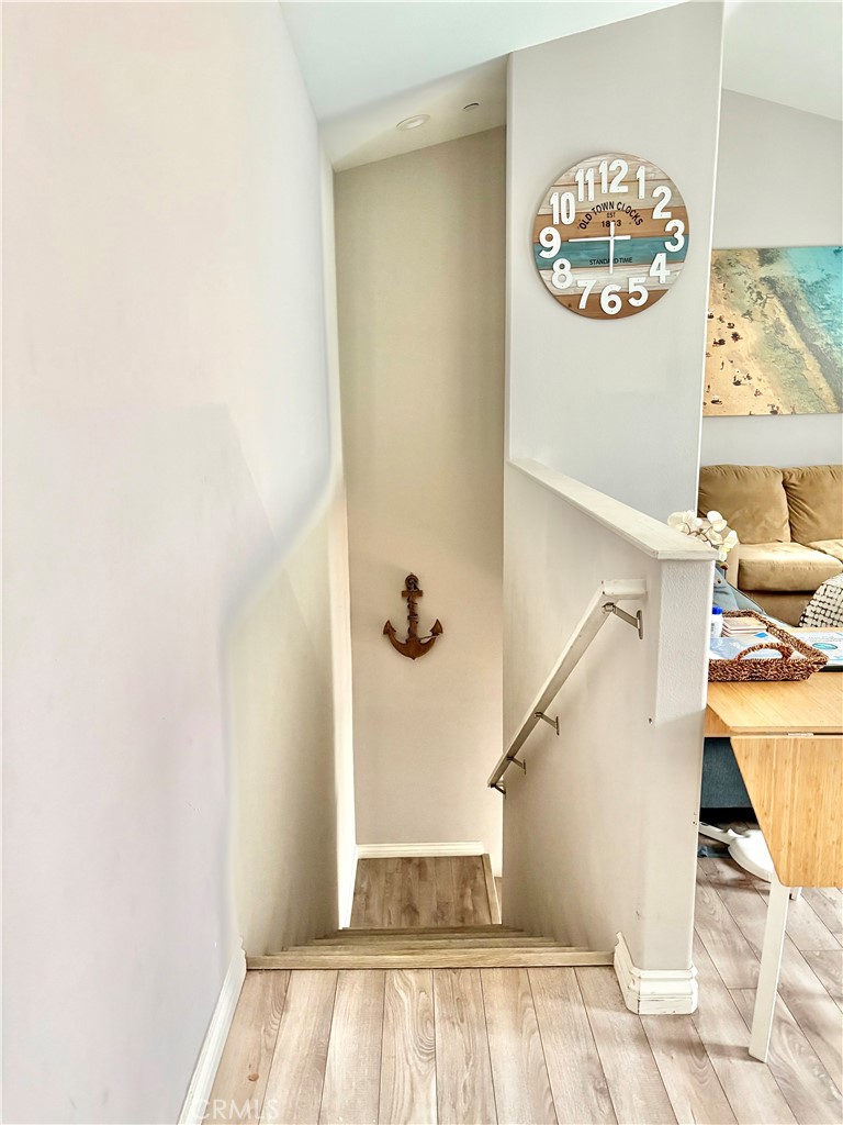 Staircase descending beside a furnished living room, with an anchor decoration on the stairwell wall.