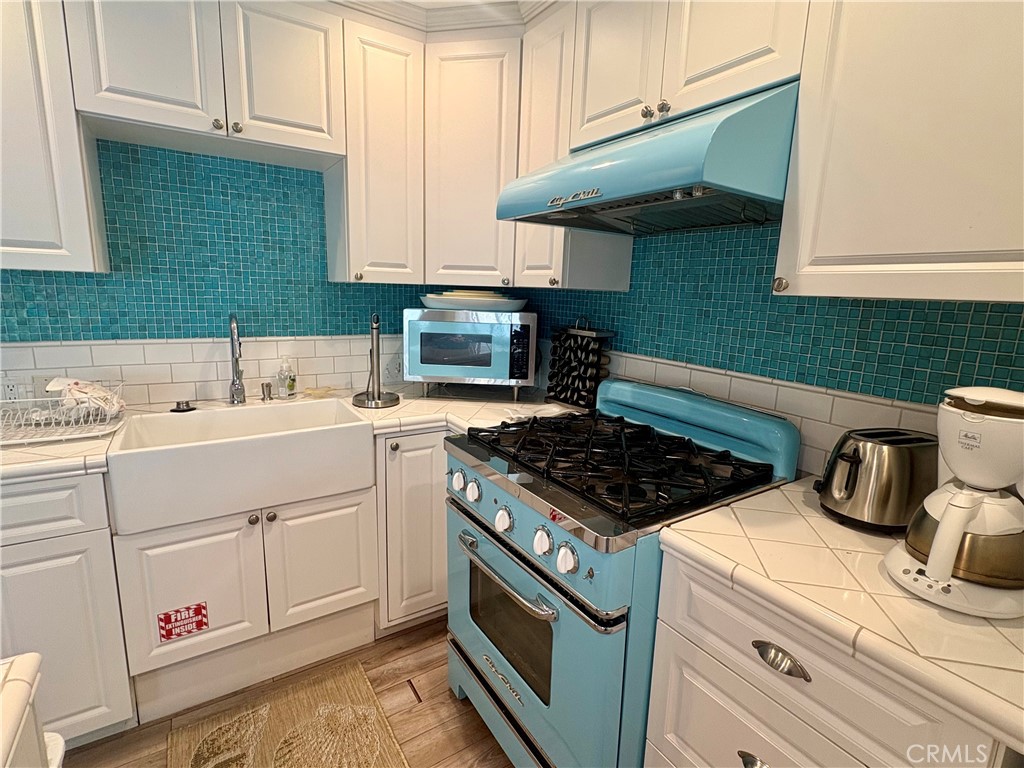 Kitchen with a turquoise Big Chill range and hood, teal tile backsplash, and deep farmhouse sink.