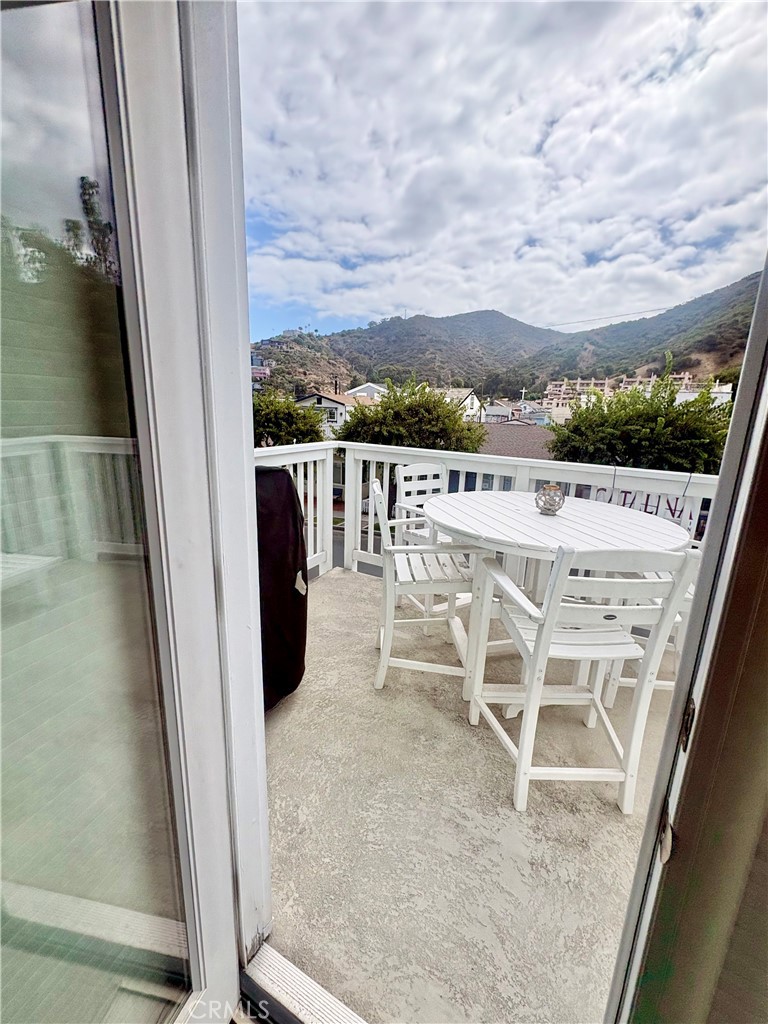 Balcony with white outdoor dining set and a view of green hills.