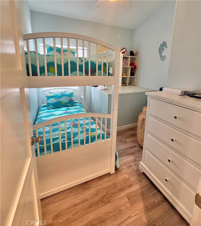 Bedroom with a white bunk bed, turquoise ocean-themed bedding, and a white dresser.