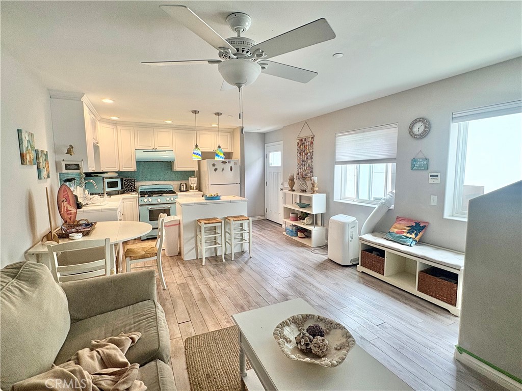 Open-plan living room and kitchen with teal backsplash, breakfast island, and large windows.