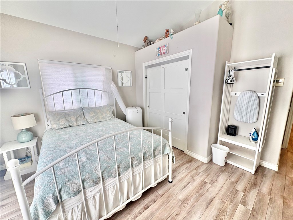 Furnished bedroom with pale blue bedding, white closet doors, and a compact ironing station.