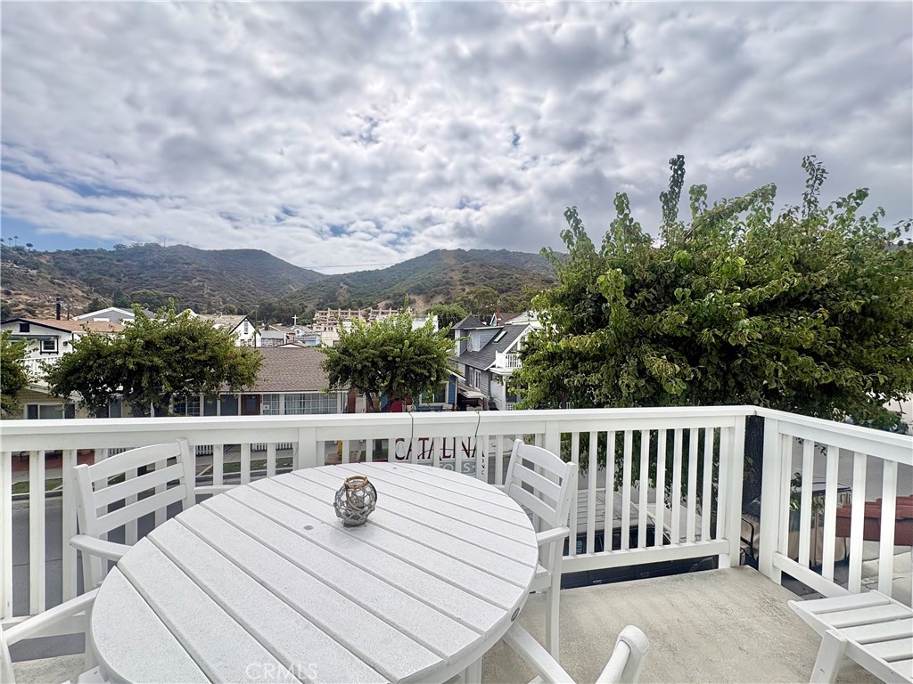 Deck with white patio furniture overlooking neighborhood homes and green hills.