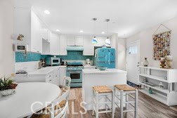 Kitchen with white cabinetry, turquoise backsplash, and matching turquoise refrigerator.