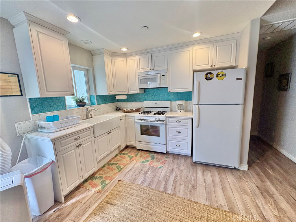 Kitchen with white cabinets, turquoise tile backsplash, and white appliances.