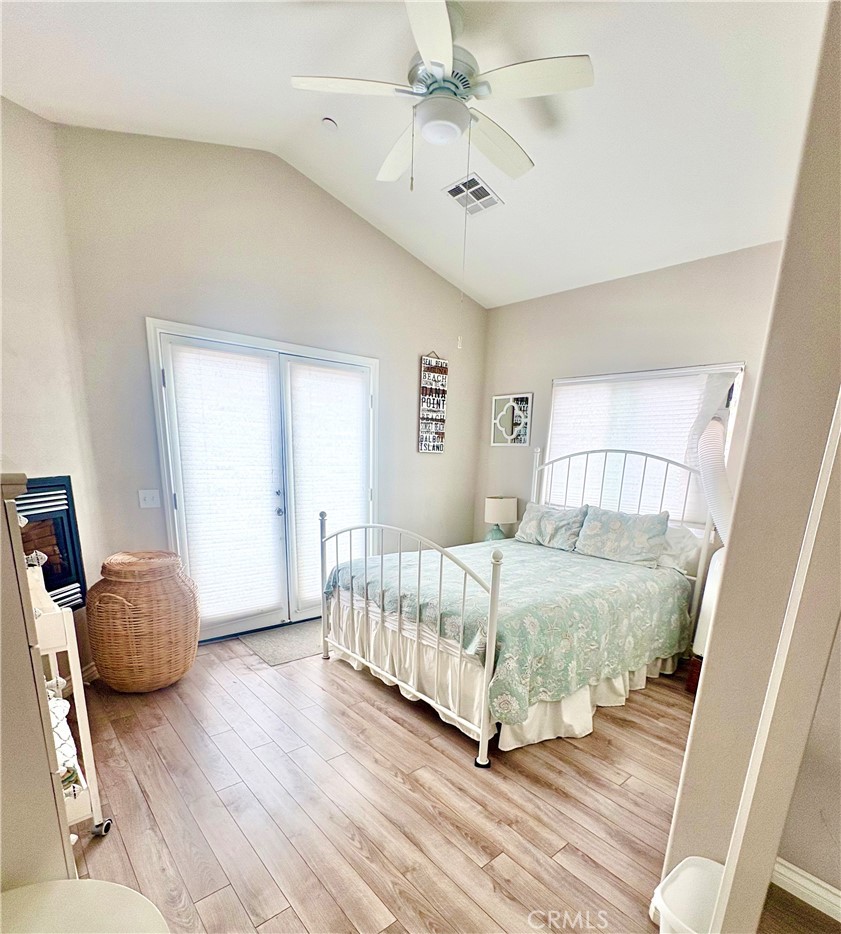 Bedroom with a white metal bed, pale aqua bedding, vaulted ceiling, and sliding glass doors.