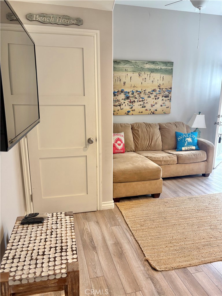 Living room with a tan sectional, beach-themed artwork, woven rugs, and light wood floors.