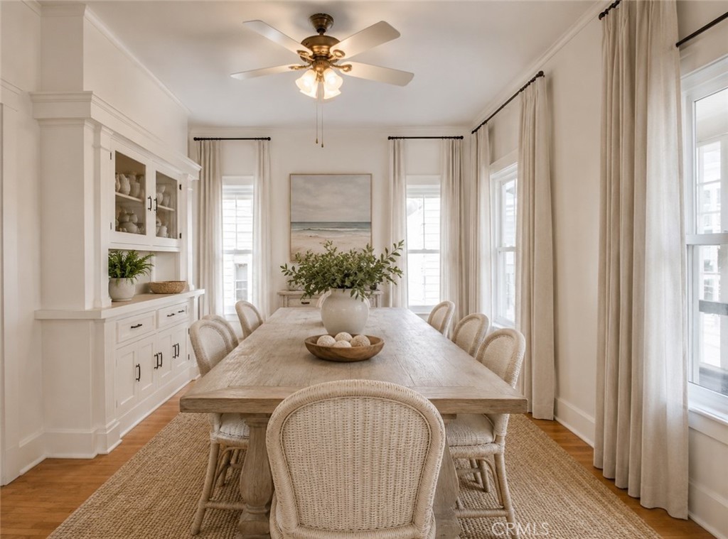 Bright dining room with a long wood table, woven chairs, and built-in white cabinetry.
