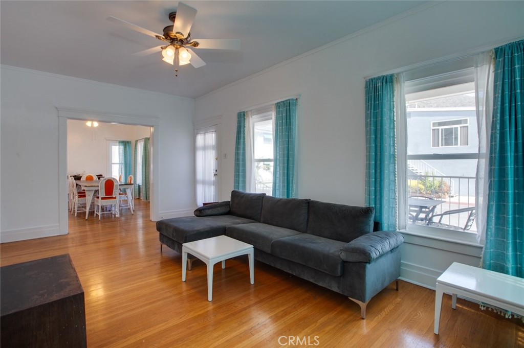Living room with gray sectional, hardwood floors, ceiling fan, and a dining area beyond.