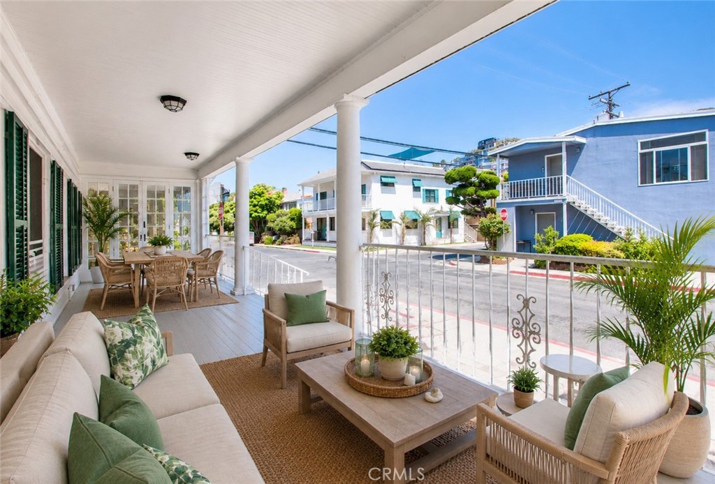 Covered porch with wicker seating and a dining table overlooking the street.