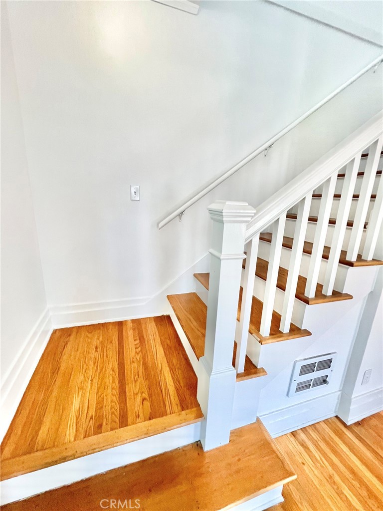 Interior staircase with white railing, hardwood treads, and a warm-toned hardwood landing.