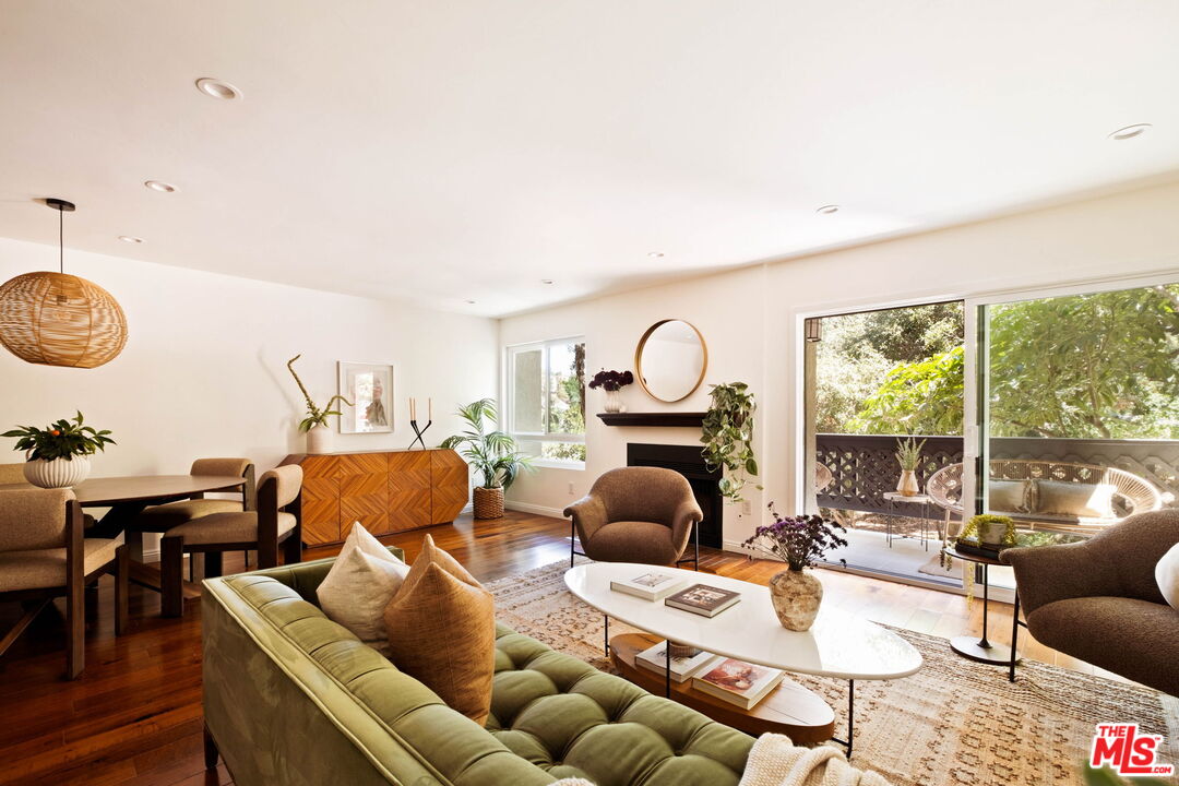 Living room with a green sofa, mid-century wood sideboard, and sliding doors to a leafy patio.