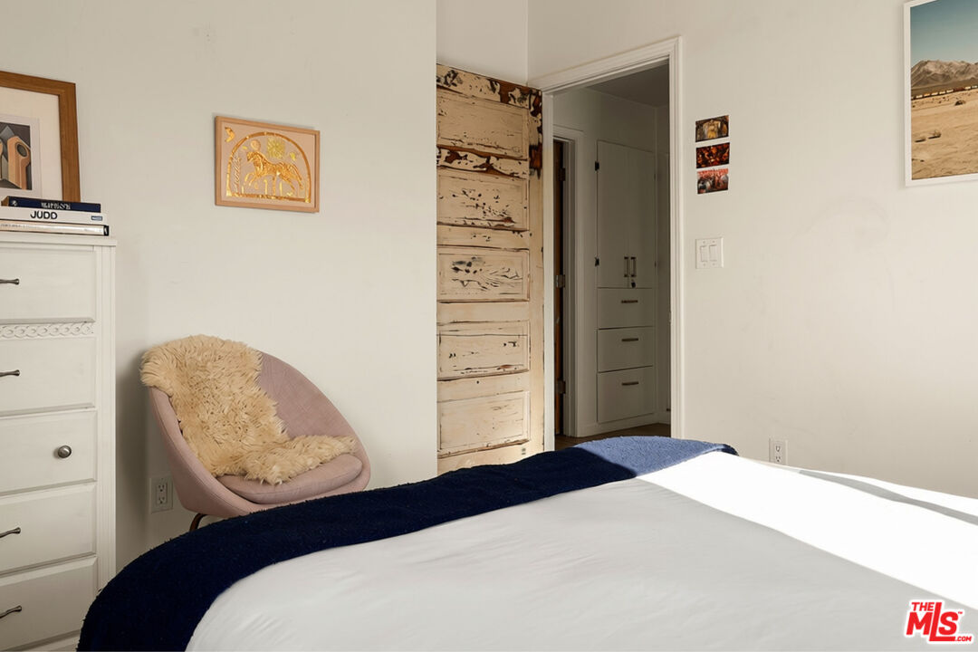Bedroom with a navy blanket, blush chair, and distressed wood sliding door.