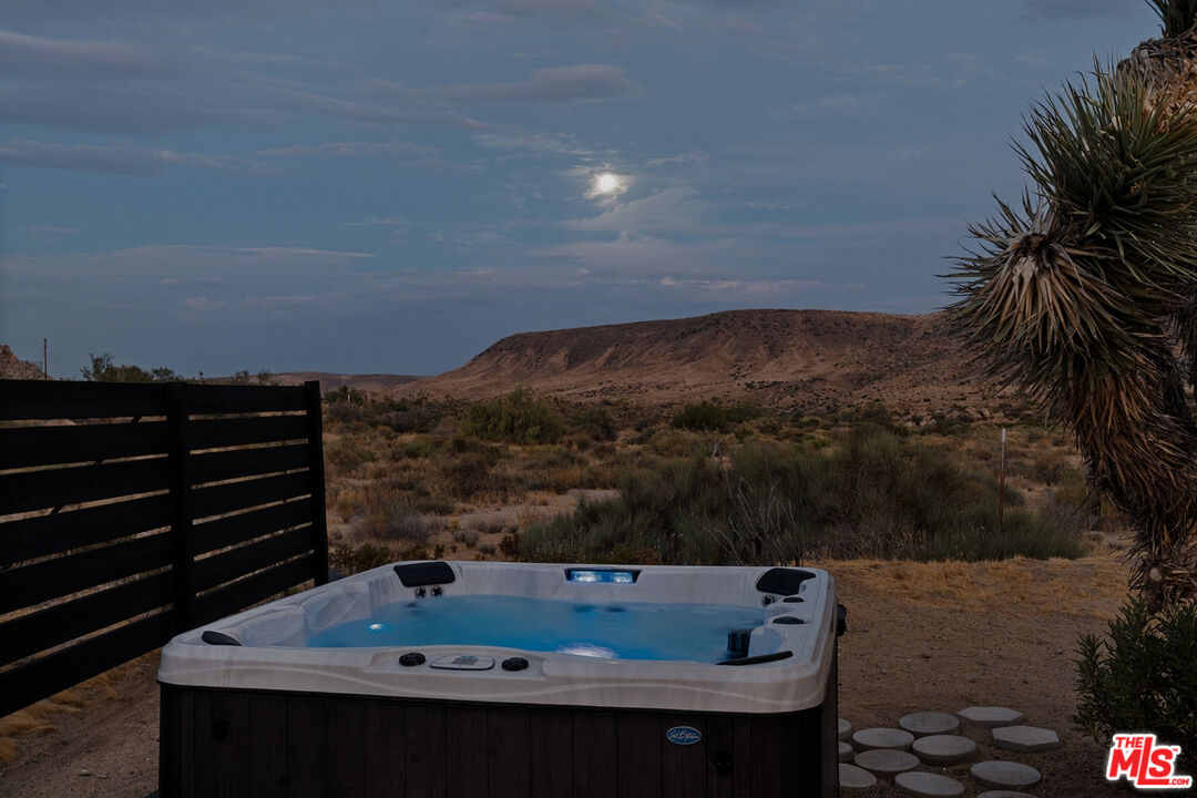Outdoor hot tub overlooking desert scrub and a rocky mountain ridge.