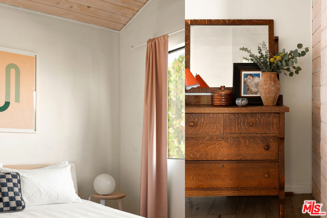 Bedroom with a white bed and a rustic wooden dresser topped by a large mirror.