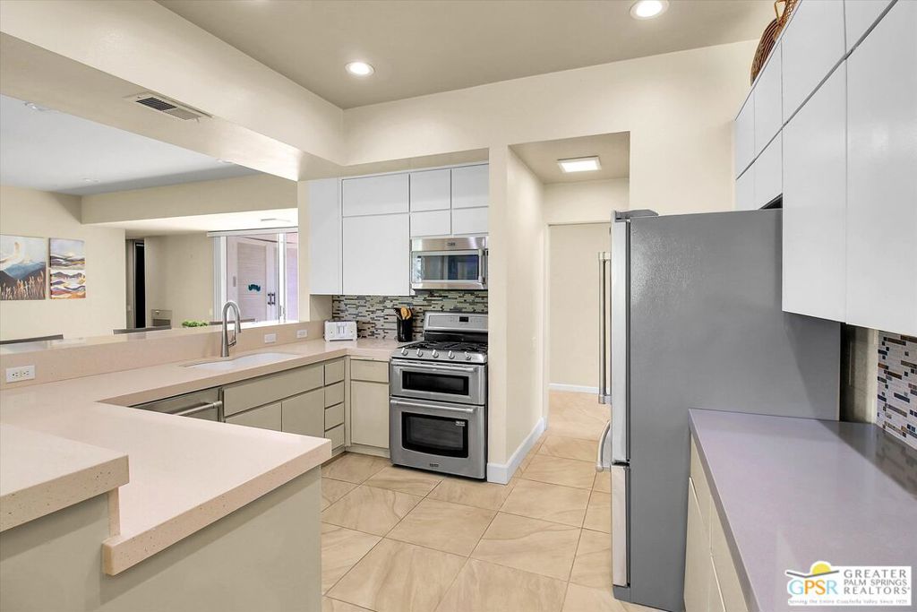 Modern kitchen with a broad peninsula, stainless steel appliances, and mosaic backsplash.