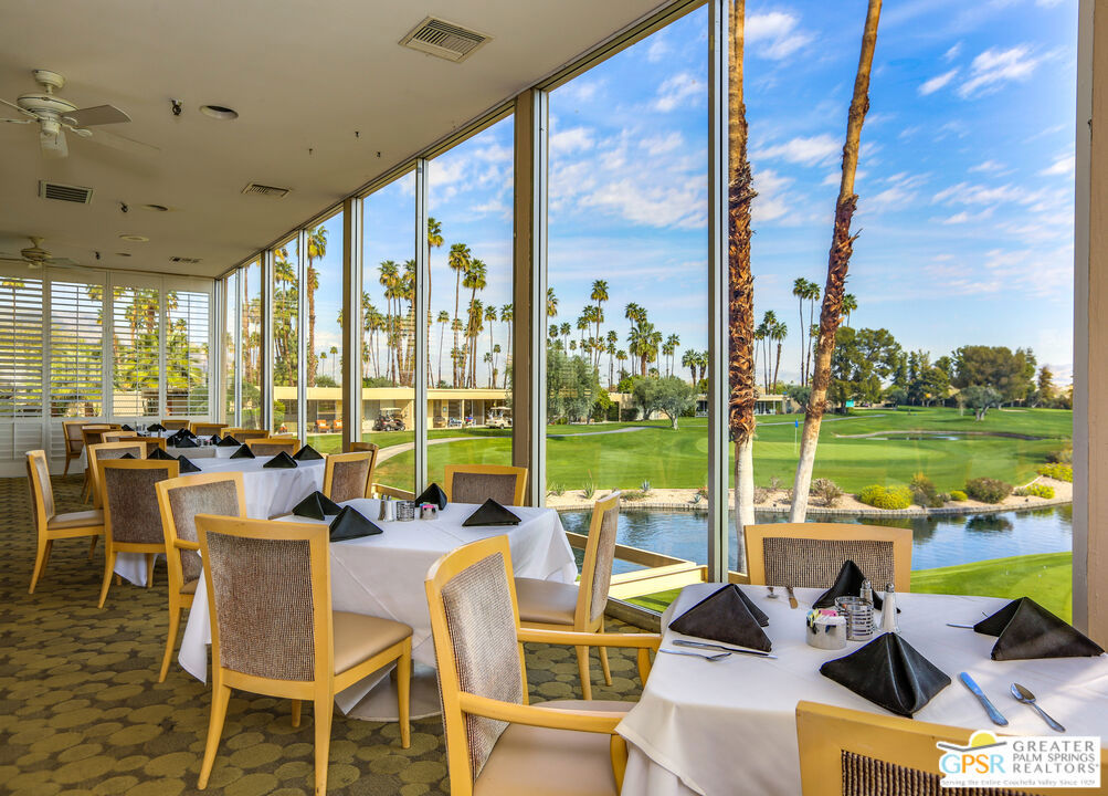 Dining room with floor-to-ceiling windows overlooking a palm-lined golf course and pond.