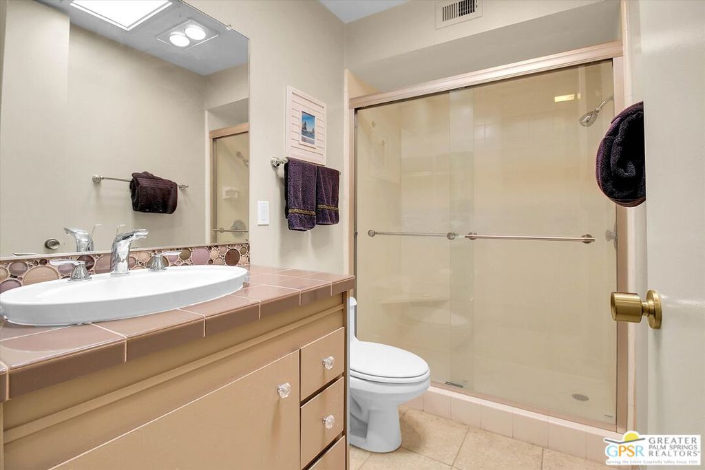 Bathroom with a pink-tile vanity, oval sink, and glass-enclosed shower.