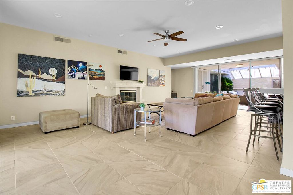 Living room with a fireplace, desert artwork, and sliding glass doors to a patio.