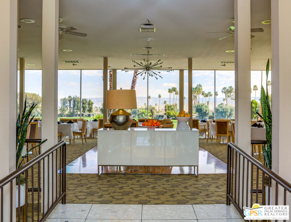 Dining room with a starburst chandelier and floor-to-ceiling windows overlooking palm trees.