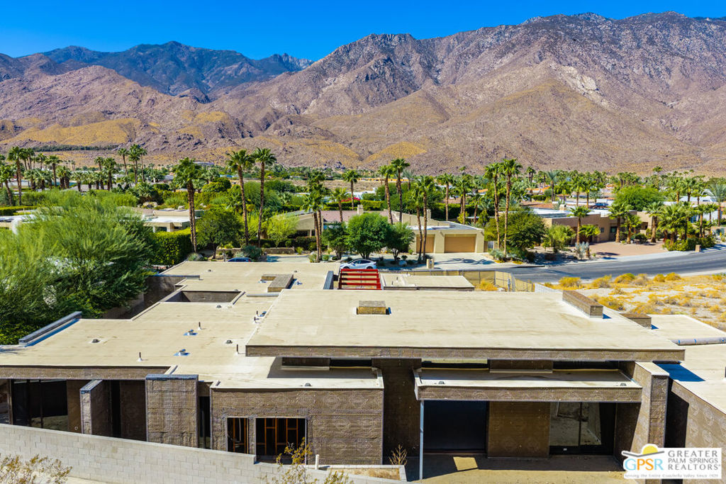 Modern flat-roofed Palm Springs home with palm trees and the San Jacinto Mountains behind it.