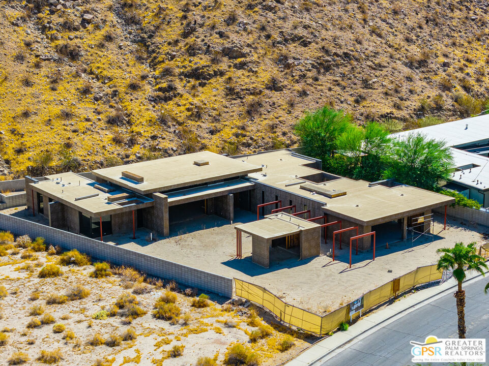 Modern flat-roof home under construction beside a dry desert hillside.