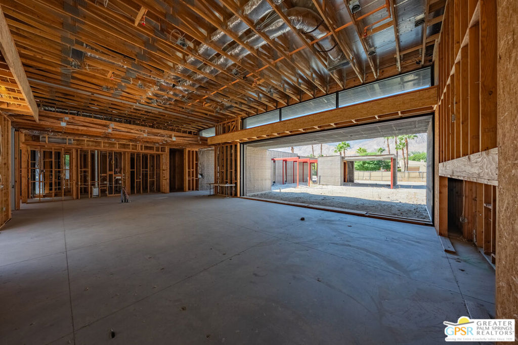 Unfinished interior with exposed framing, a concrete floor, and a wide opening to the exterior.