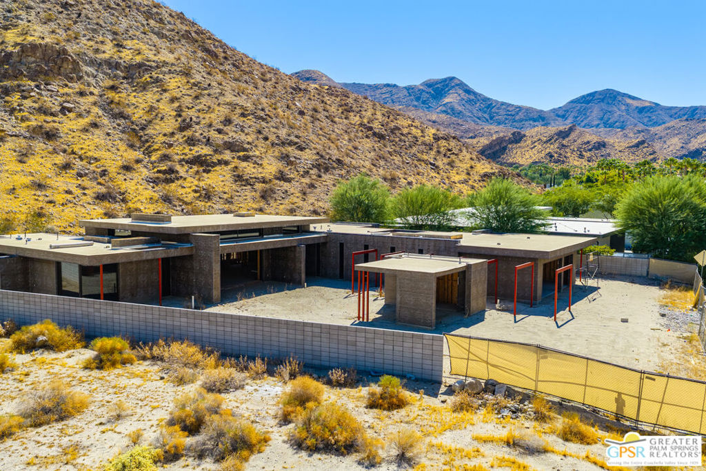 Modern home under construction in a desert lot, backed by rugged Palm Springs mountains.