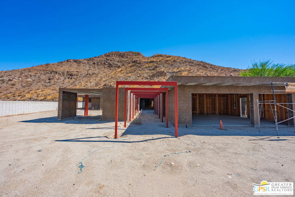 Home under construction with red steel framing and a rocky mountain backdrop.