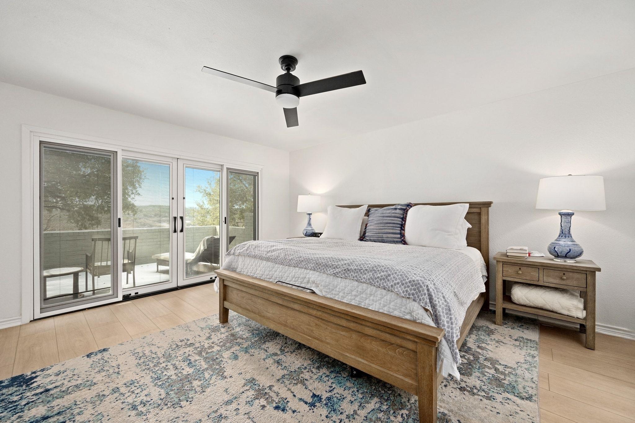 Bedroom with a wood king bed beside sliding glass doors opening onto a balcony.