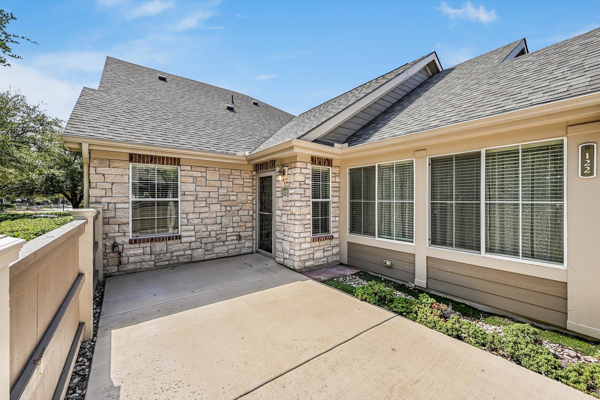 Home exterior with a stone entry, broad windows, and a concrete approach.