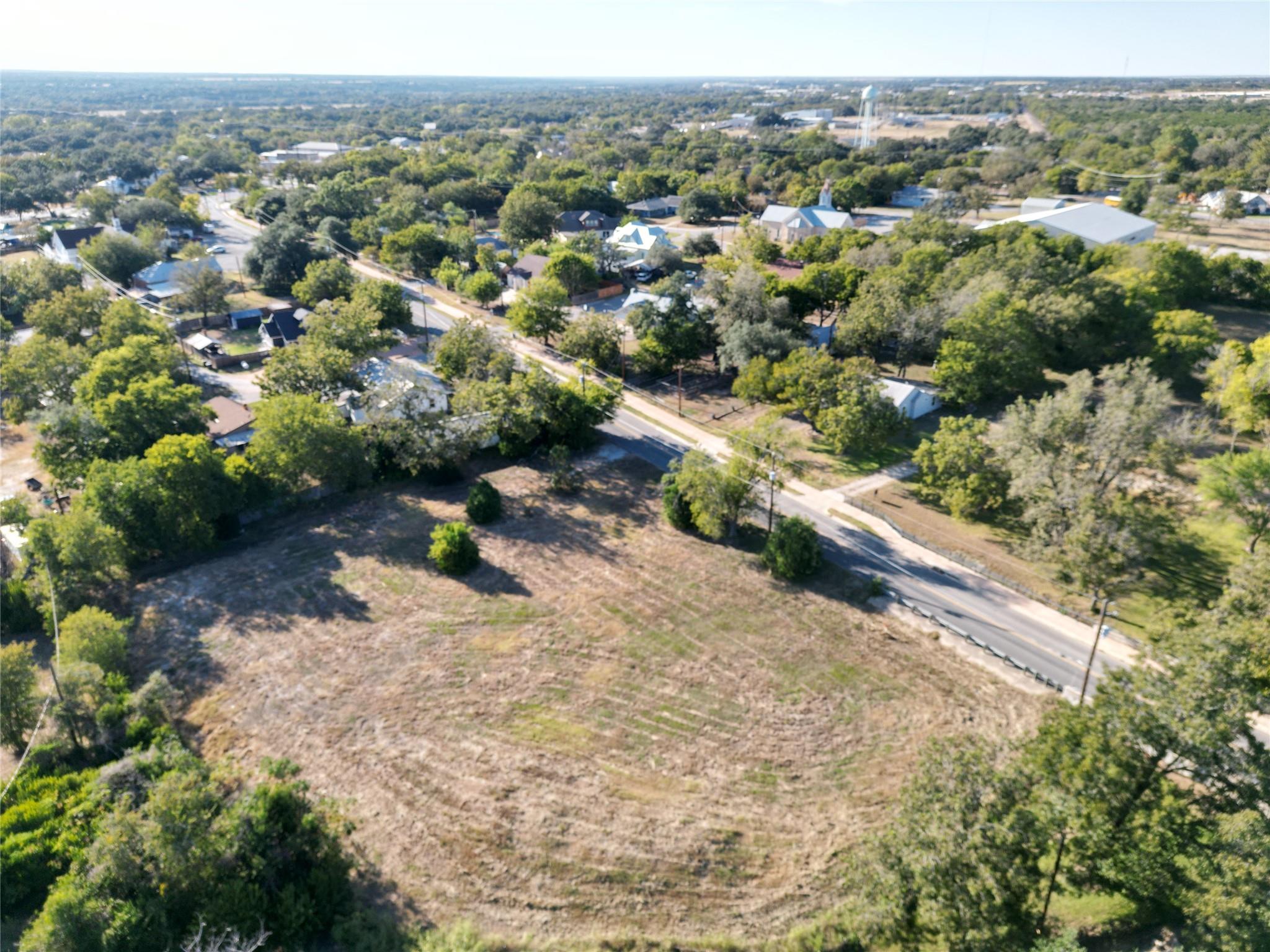 Aerial view of a vacant lot beside a road in a leafy neighborhood.