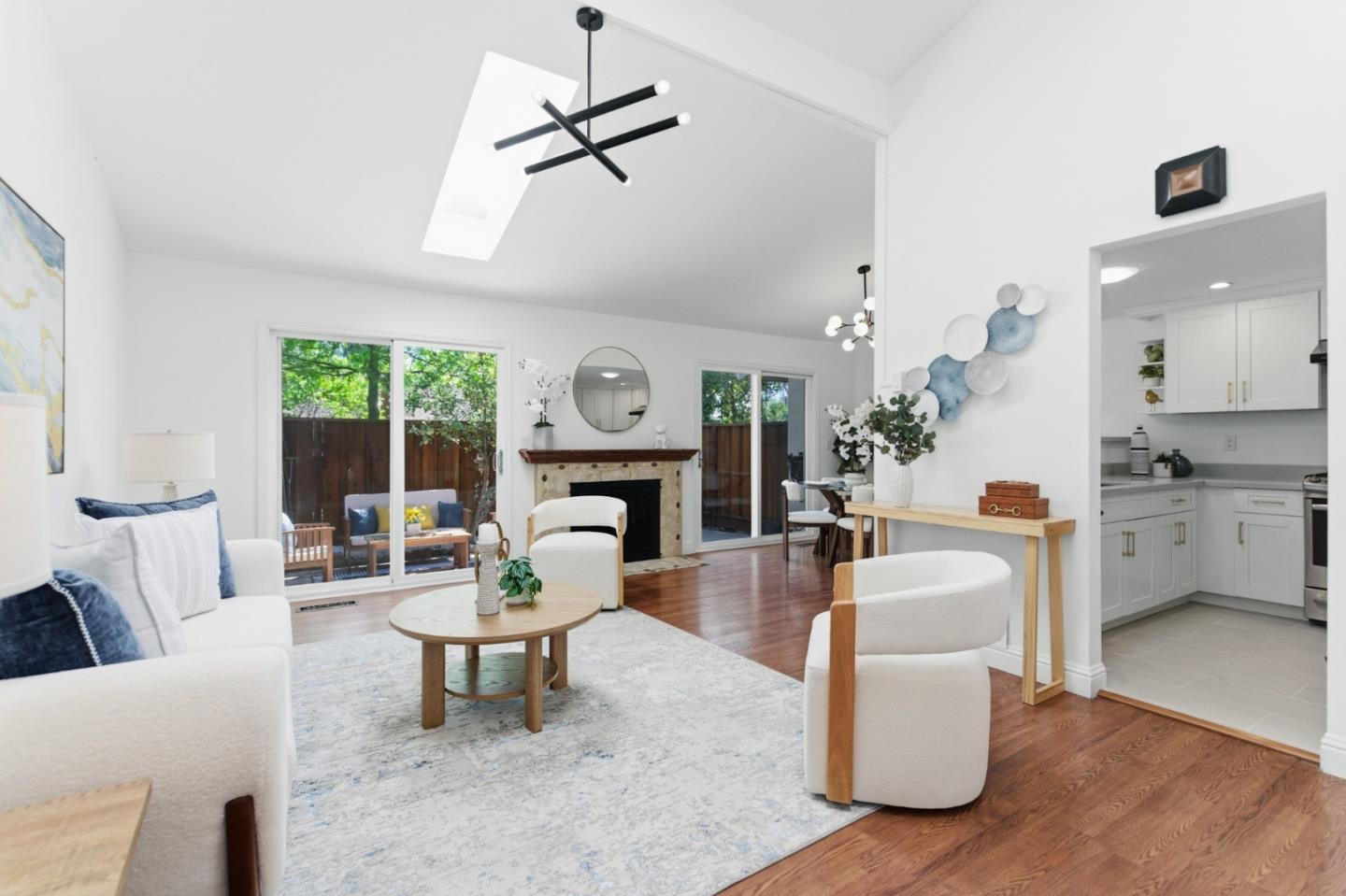 Bright living room with a fireplace, hardwood floors, and glass doors to a fenced yard.