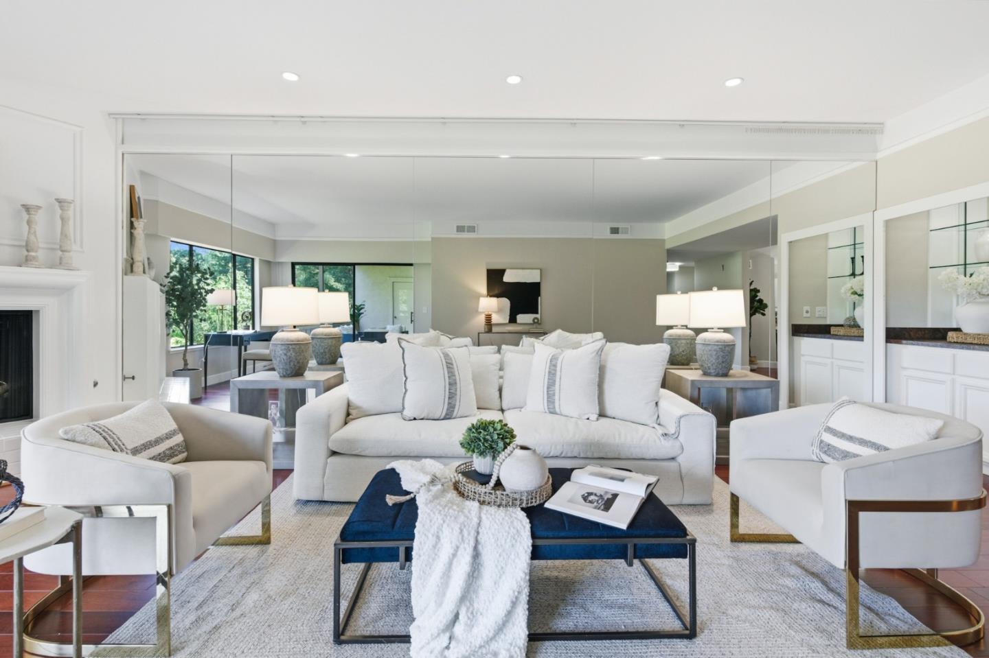 Staged living room with a white sofa, blue coffee table, fireplace, and large windows.