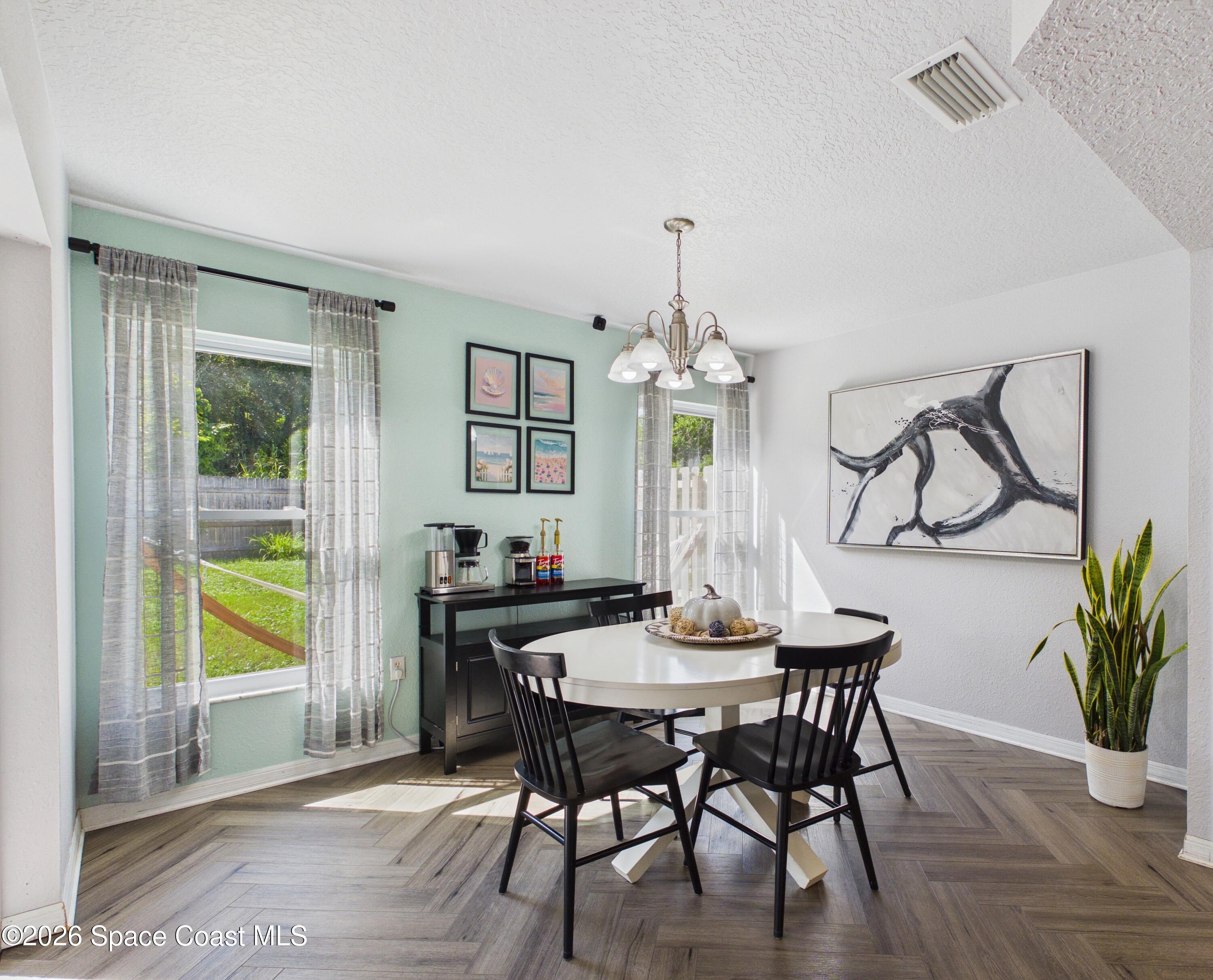 Dining area with a round white table, black chairs, mint-green wall, and large abstract painting.