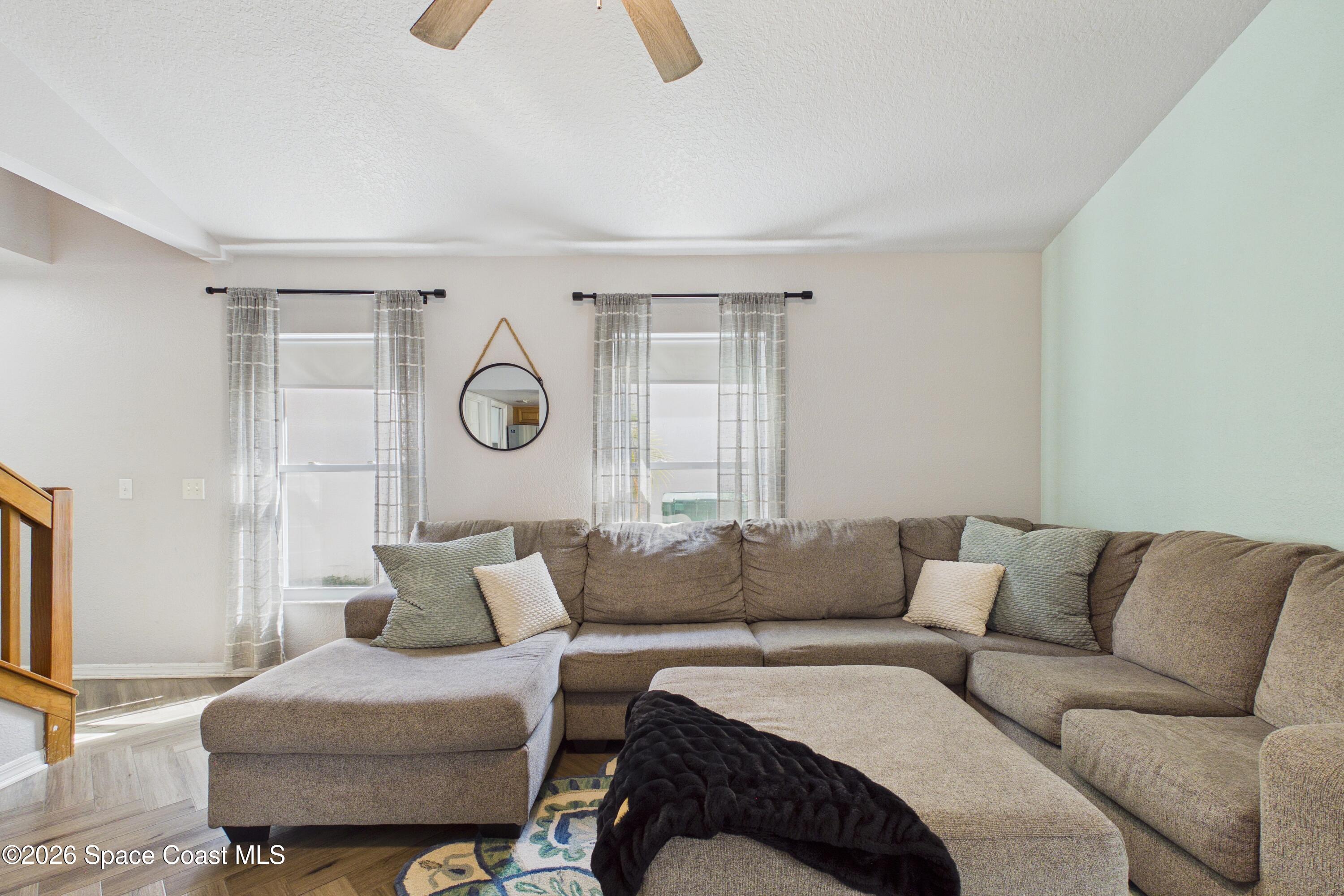 Living room with a large gray sectional, chaise, and two curtained windows.