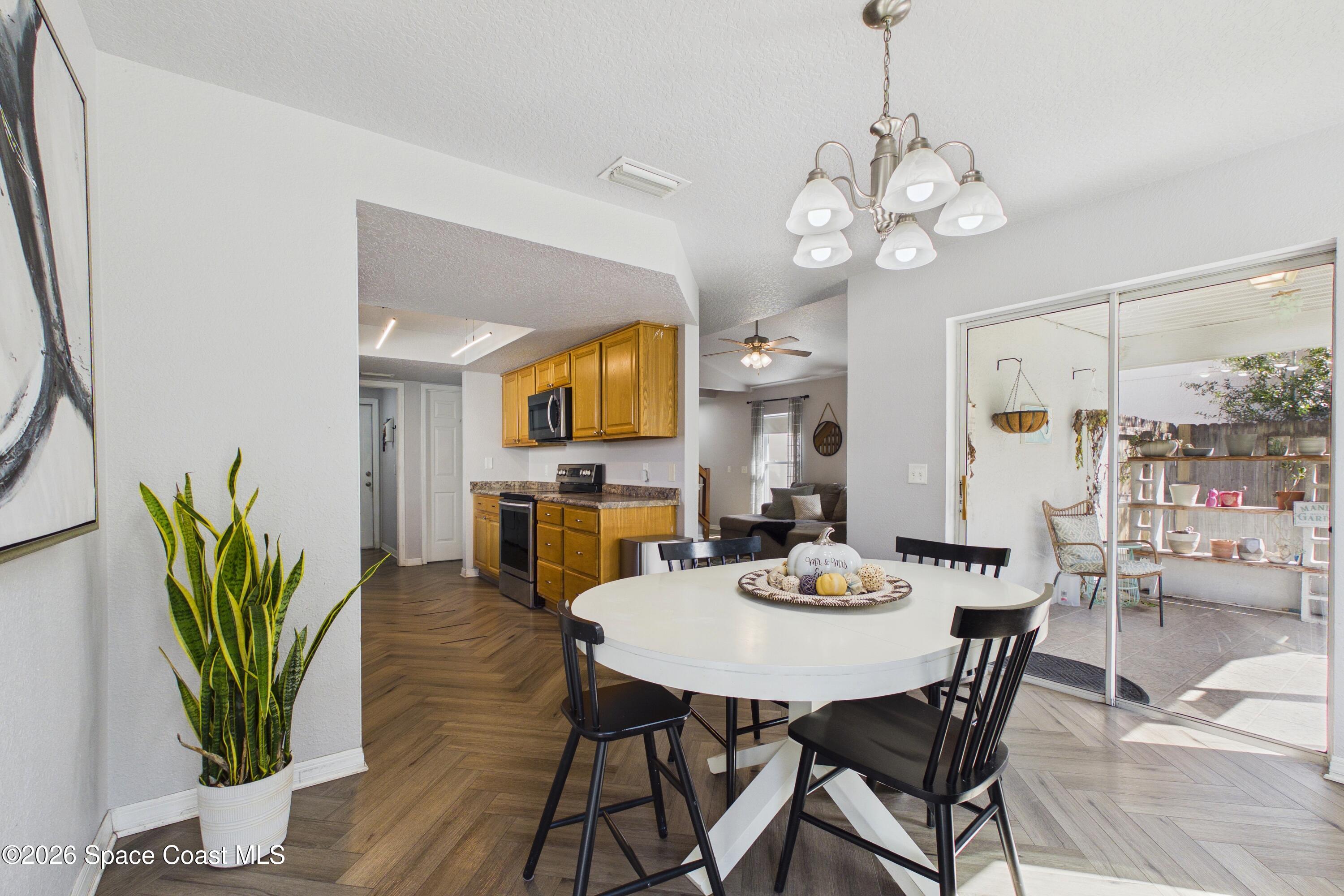 Dining area with a white oval table beside a honey-colored kitchen and sliding glass patio doors.