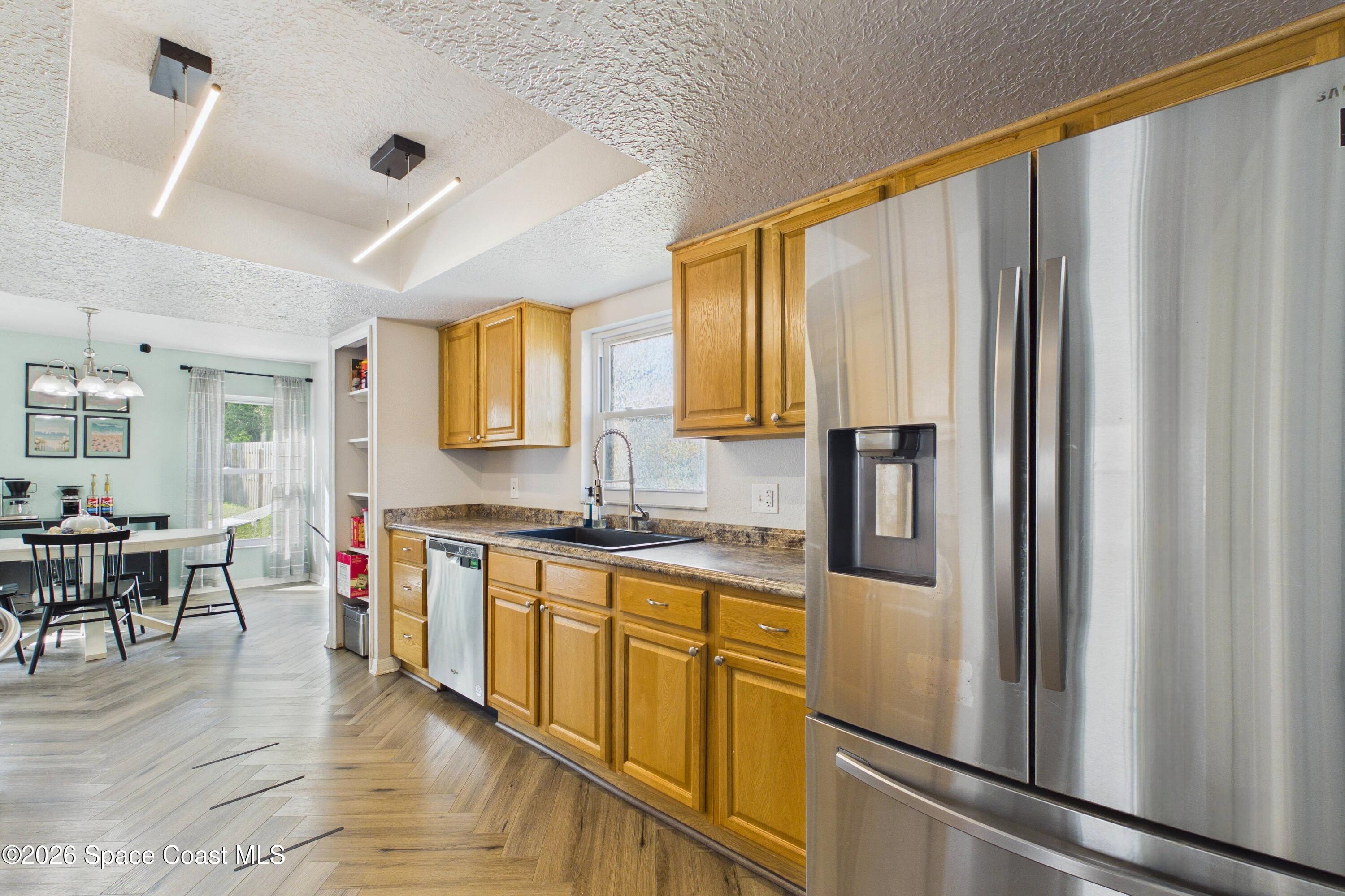 Kitchen with honey-colored cabinets, stainless steel appliances, and an adjoining dining area.