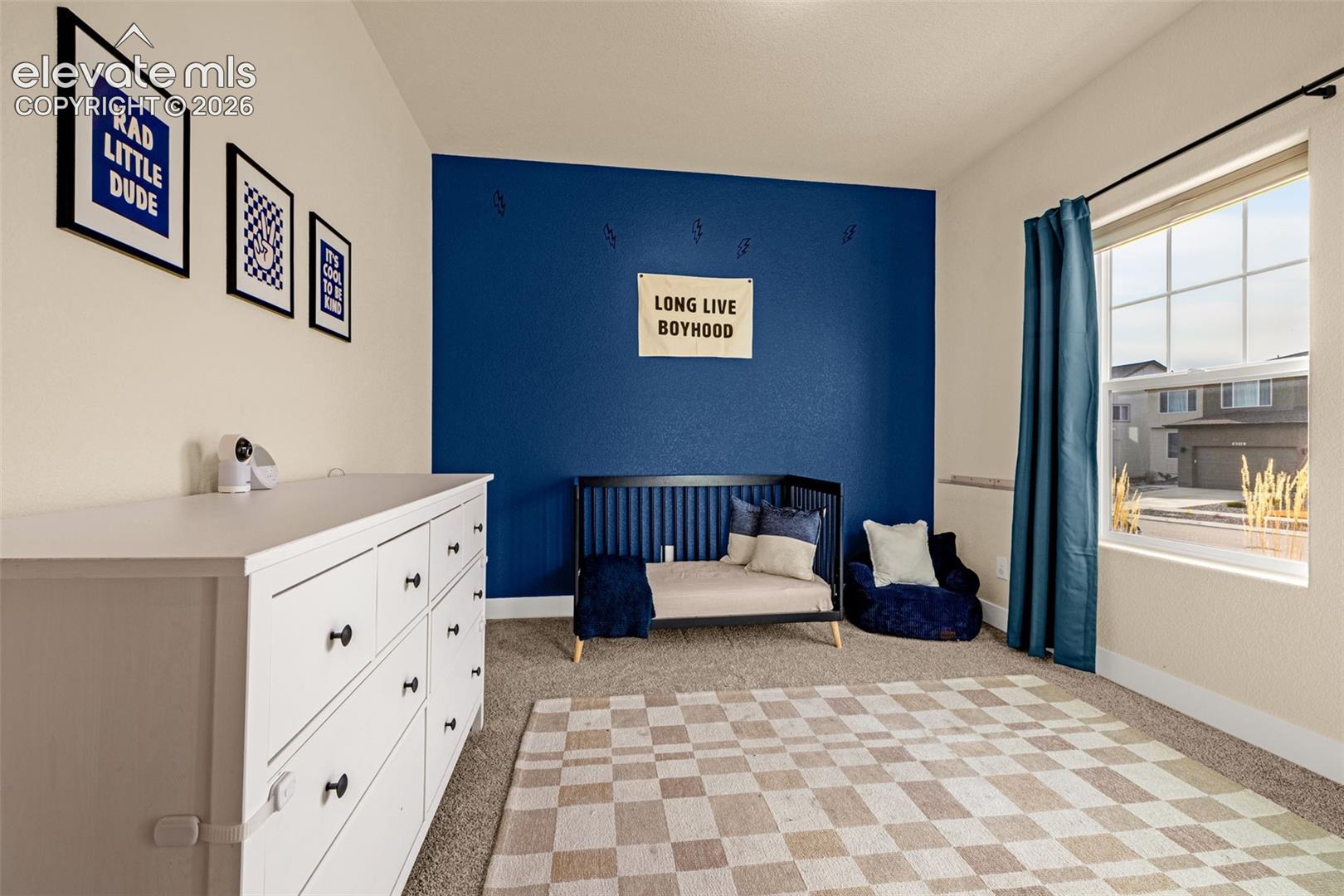 Child’s bedroom with a blue accent wall, daybed, and large window.