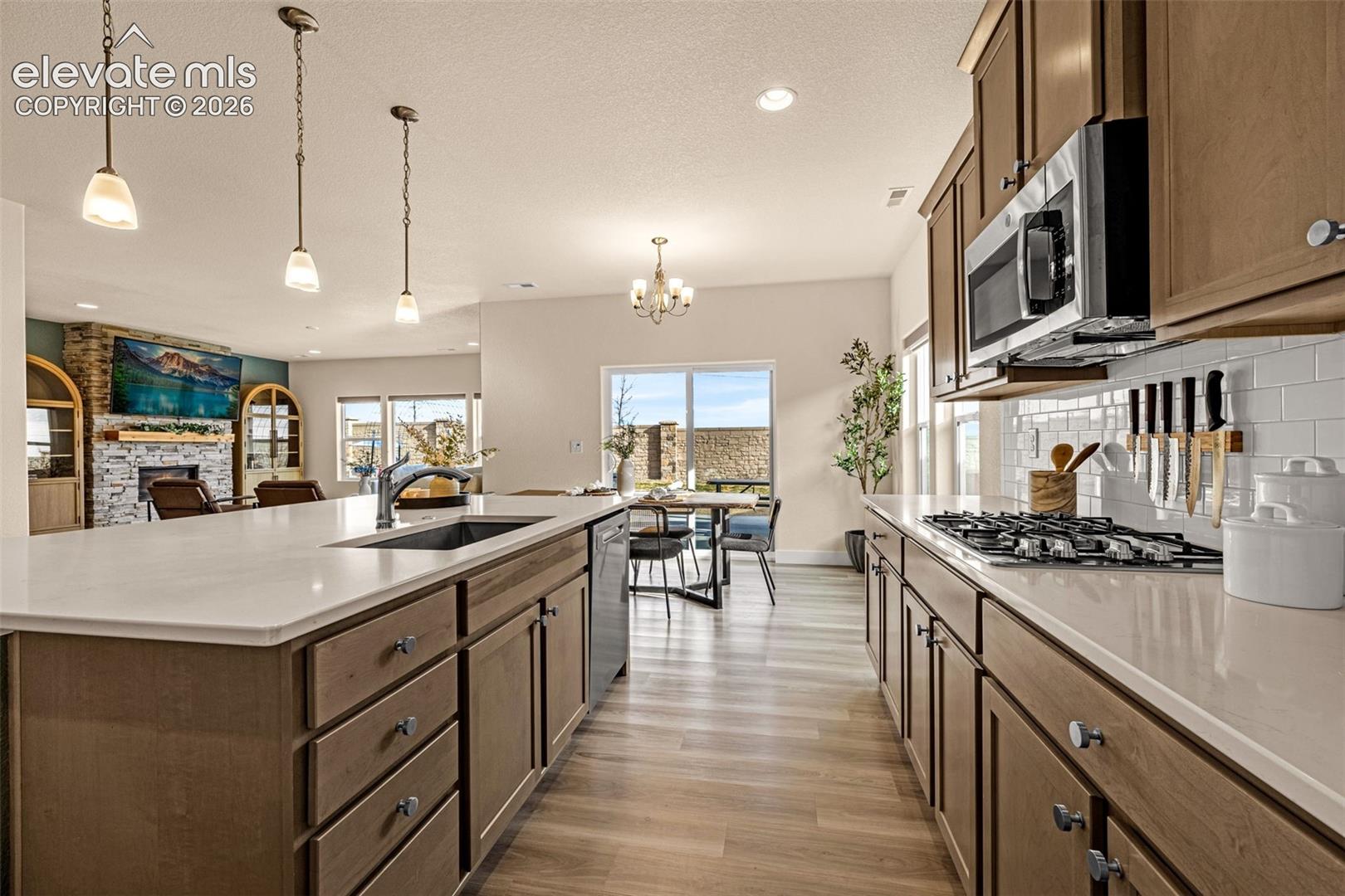 Open-plan kitchen with a large white island, warm wood cabinets, and stainless steel appliances.