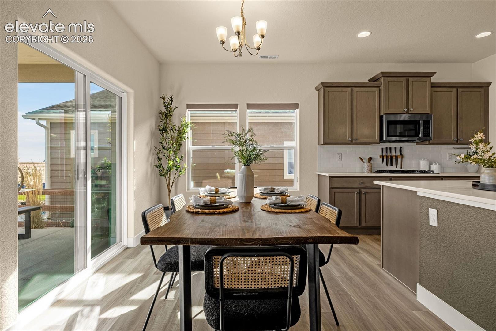 Dining area and kitchen with a dark wood table, brown cabinets, and sliding doors to the patio.
