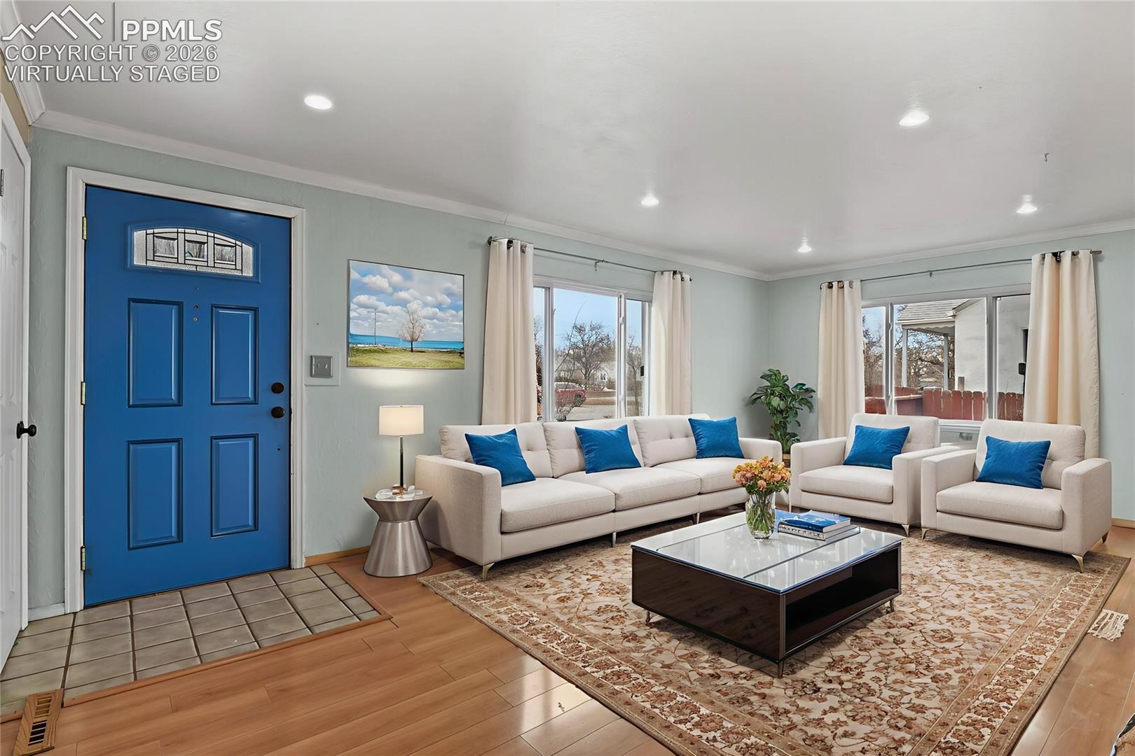 Staged living room with a vivid blue front door, cream seating, and large windows.