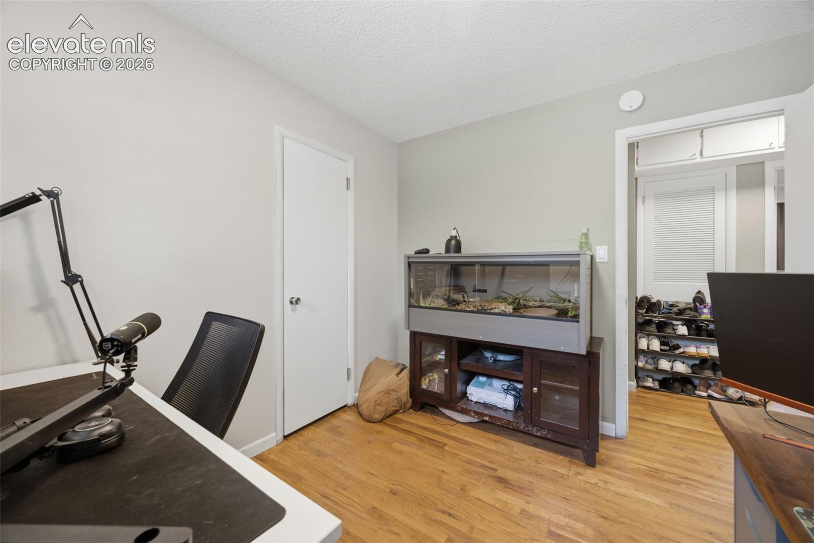 Home office with a desk, black chair, and large terrarium on a cabinet.