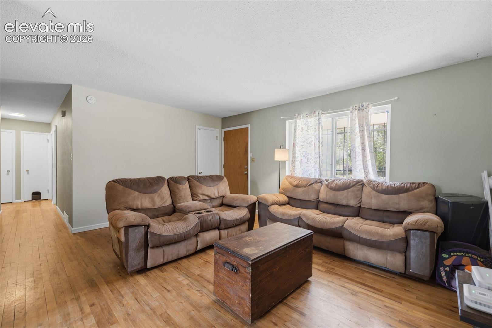 Living room with brown reclining sofas, a wooden trunk coffee table, and hardwood floors.